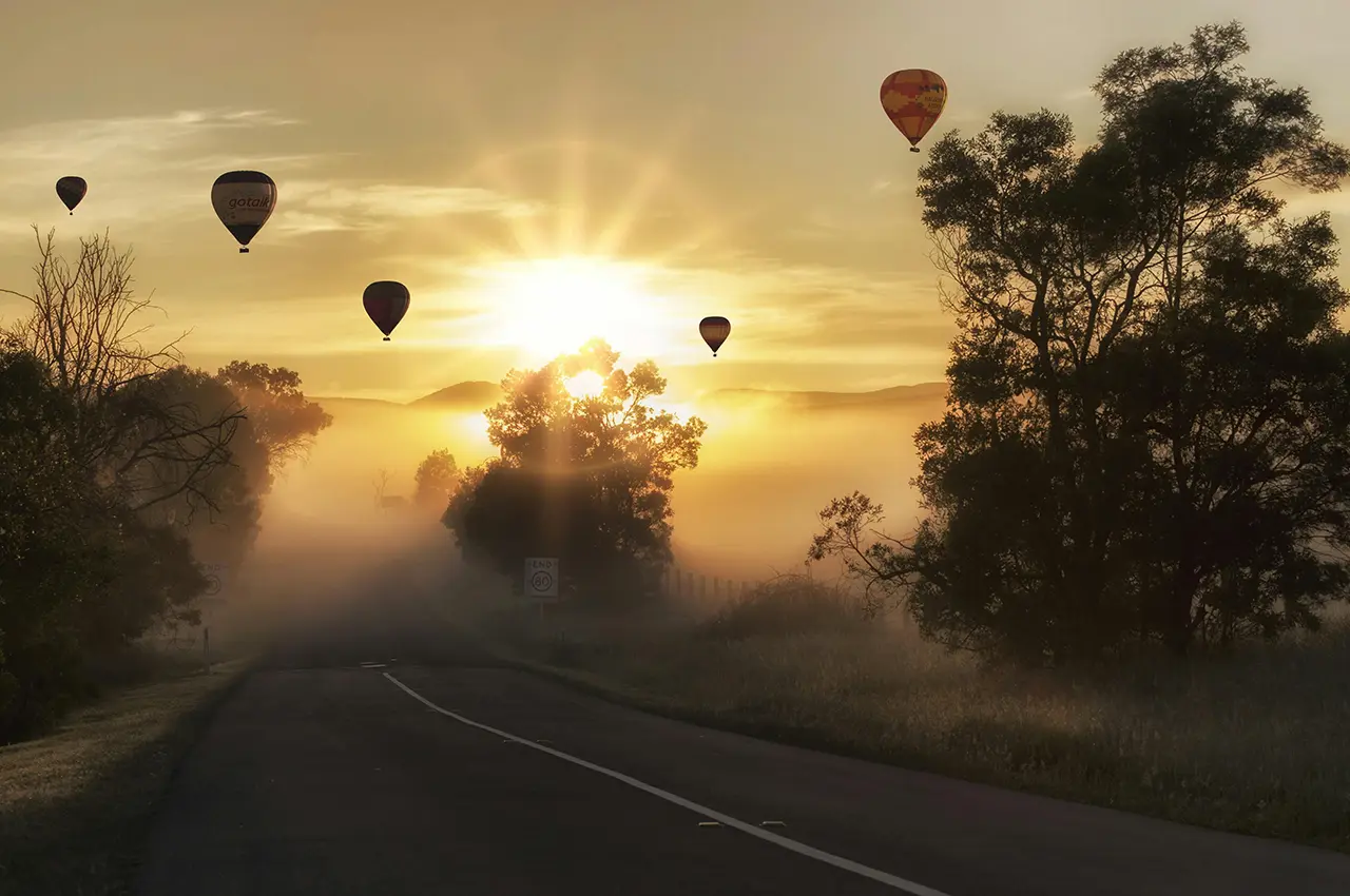 hot air balloons ascending above a foggy landscape