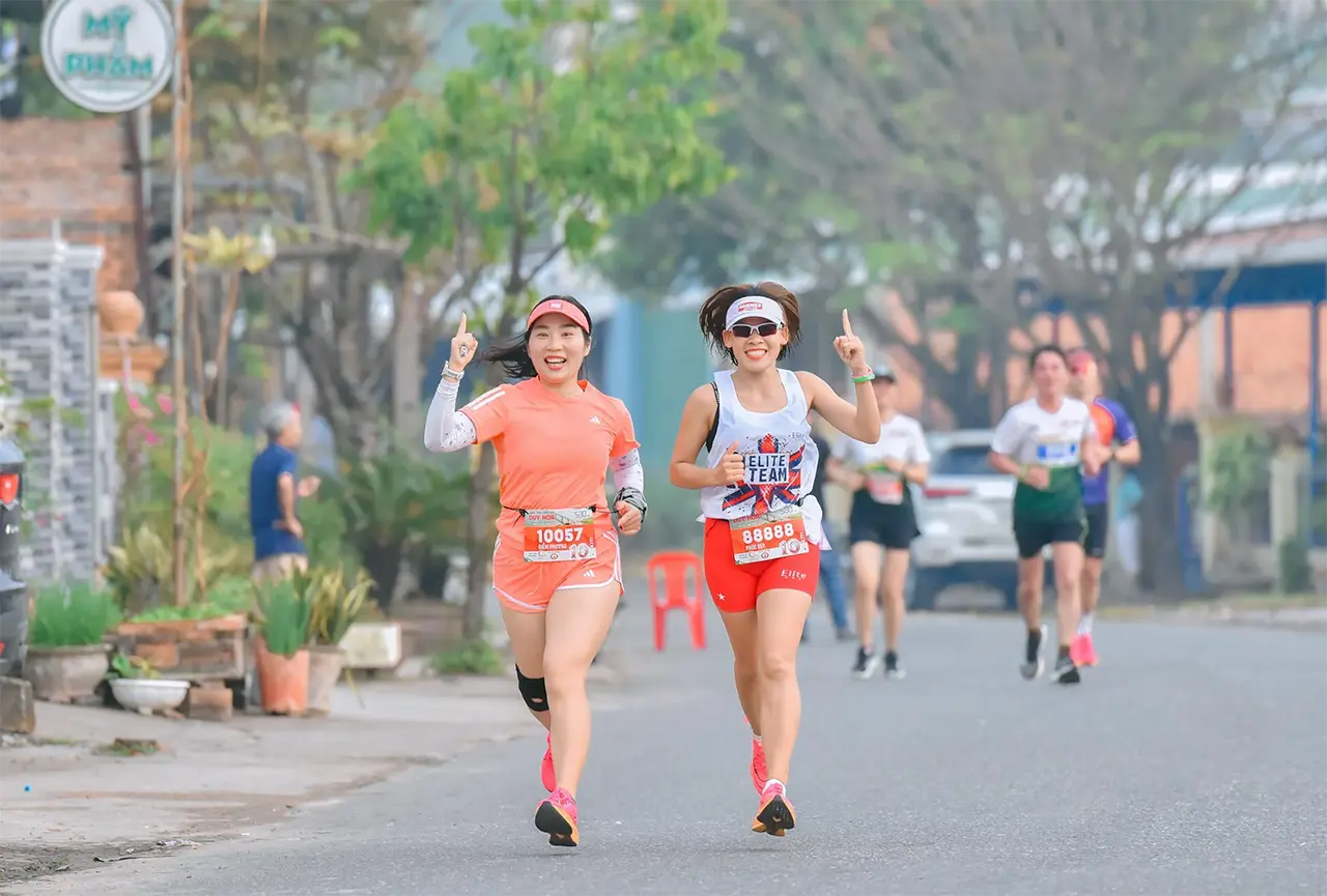 women running in a marathon race with number one hand gestures